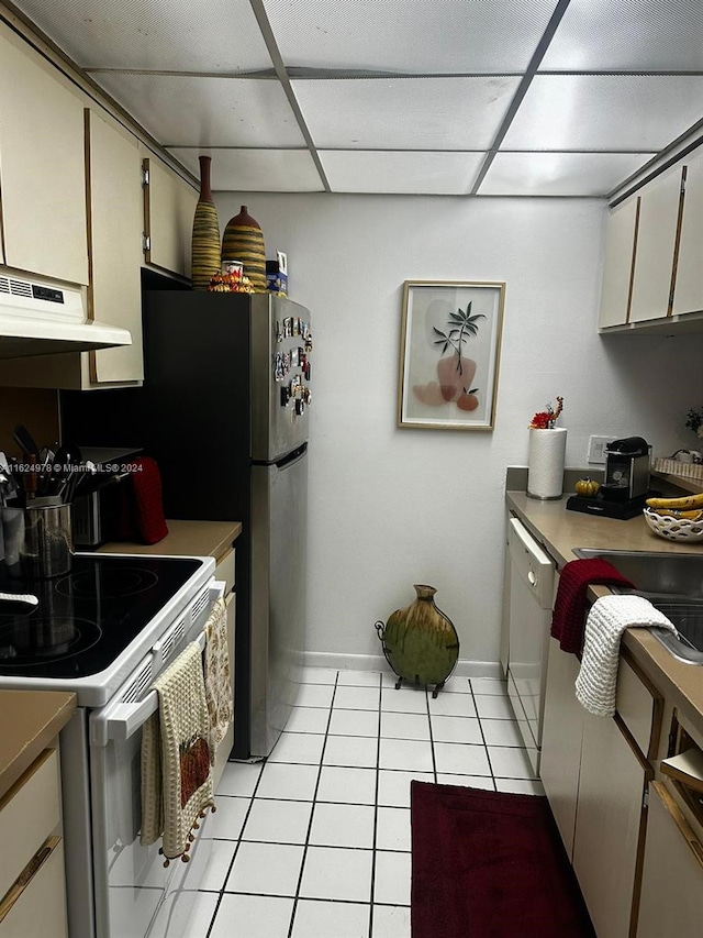 kitchen with a drop ceiling, stove, range hood, dishwasher, and light tile patterned floors