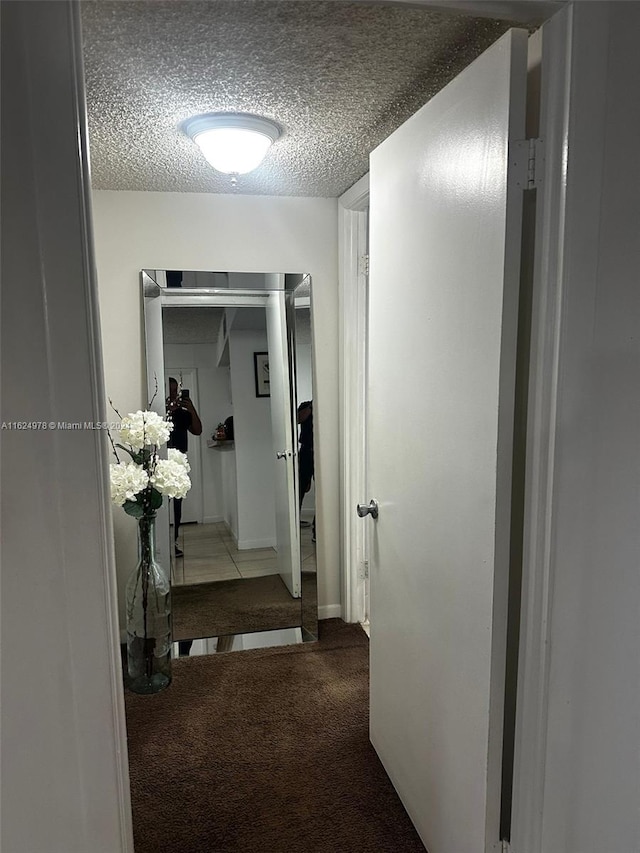 hall featuring a textured ceiling and light colored carpet