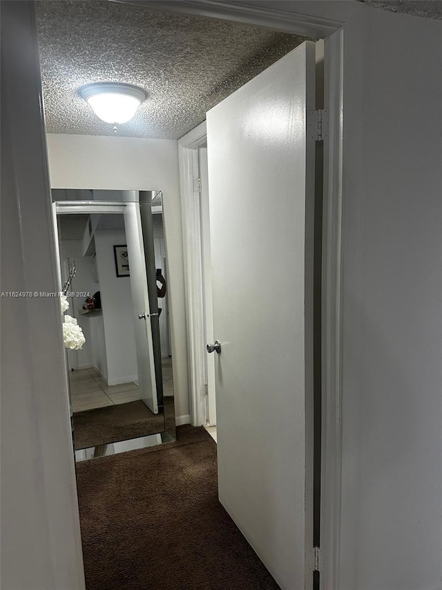 hallway with carpet flooring and a textured ceiling