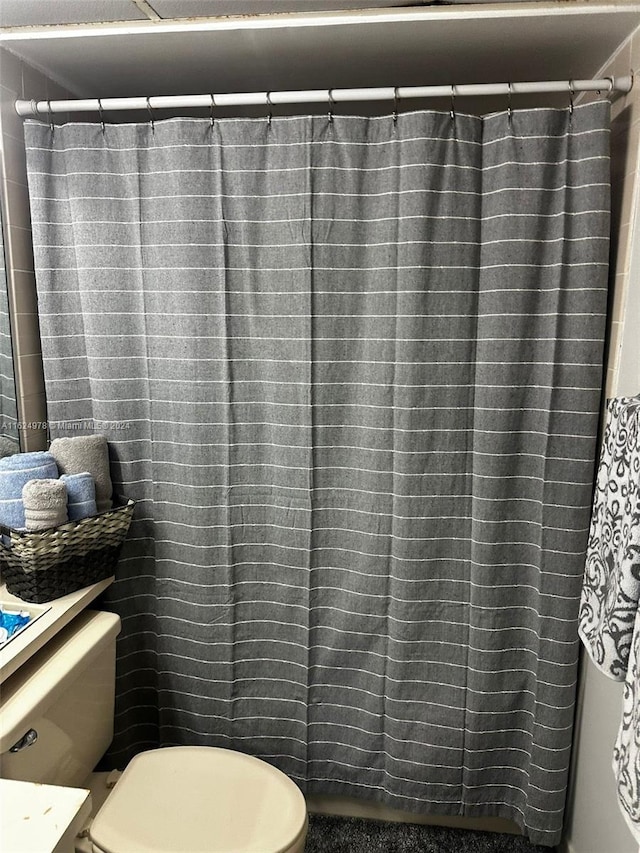 bathroom with curtained shower and toilet