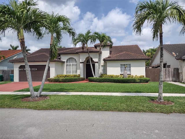 mediterranean / spanish-style house featuring a garage and a front lawn