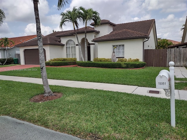 mediterranean / spanish house with a garage and a front yard