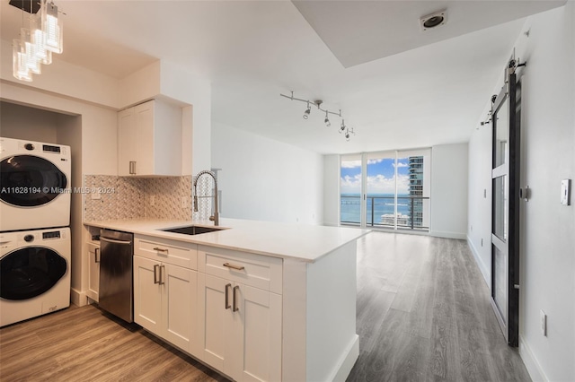 kitchen with dishwashing machine, white cabinetry, sink, kitchen peninsula, and backsplash