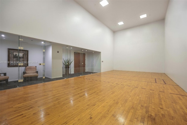 interior space with light wood-type flooring and a towering ceiling