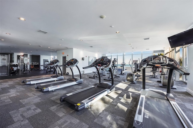 exercise room featuring floor to ceiling windows and dark carpet