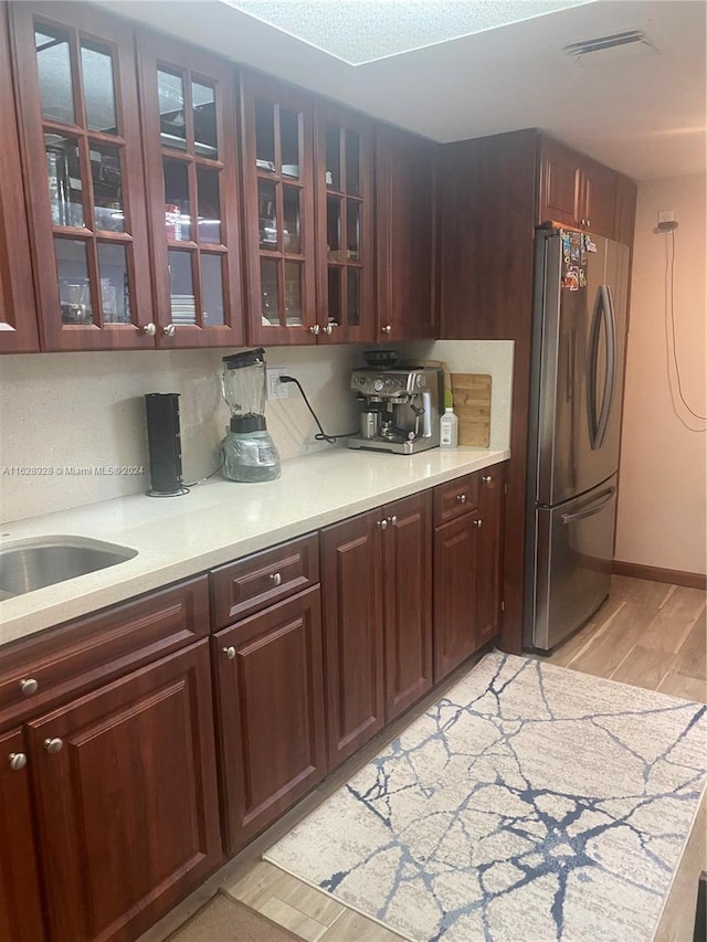 kitchen featuring decorative backsplash, light wood-type flooring, and stainless steel refrigerator