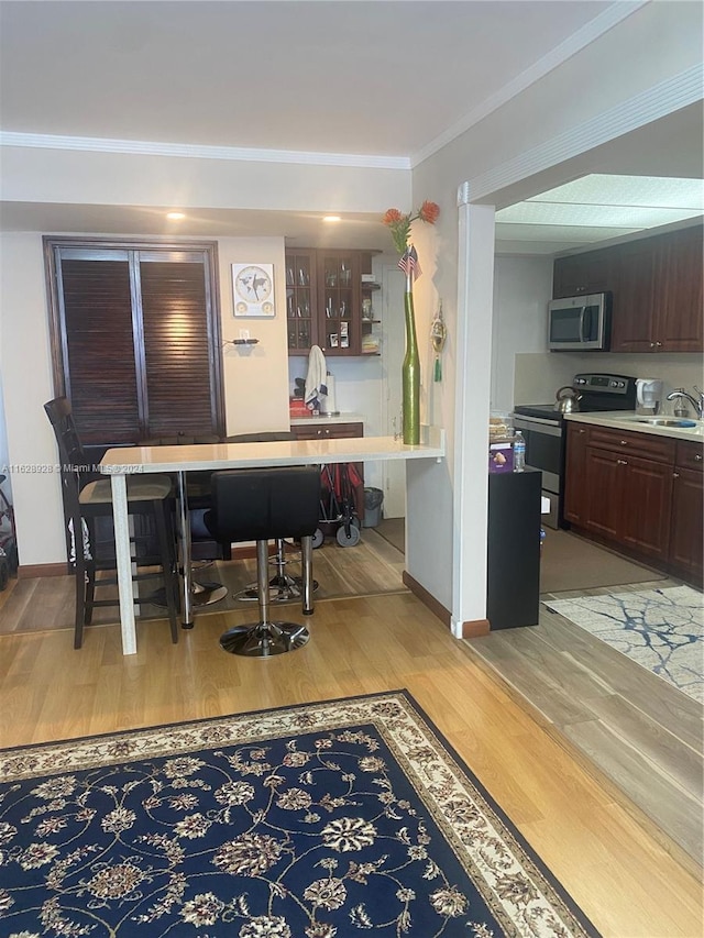 dining space featuring sink, ornamental molding, and light hardwood / wood-style floors