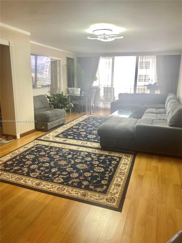 living room with ornamental molding, plenty of natural light, and light wood-type flooring