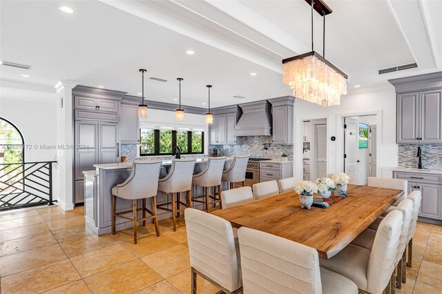 dining area featuring light tile patterned flooring, ornamental molding, a chandelier, and sink