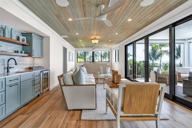 living room featuring sink, beverage cooler, ornamental molding, light hardwood / wood-style floors, and wooden ceiling