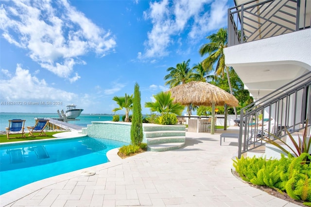 view of swimming pool with a bar, a patio, and a water view