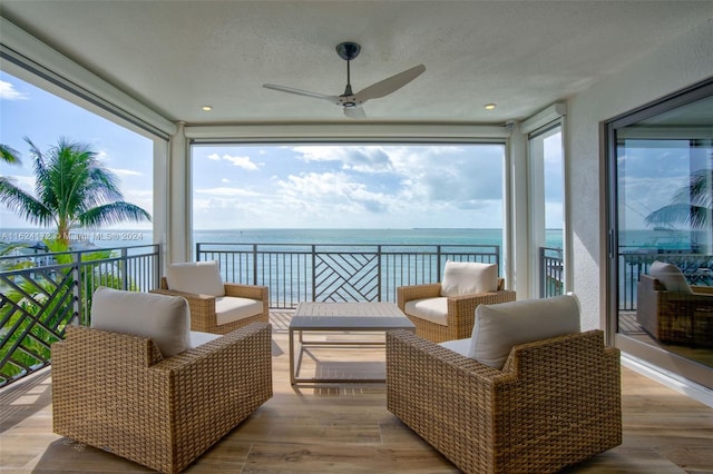 sunroom with plenty of natural light, ceiling fan, and a water view