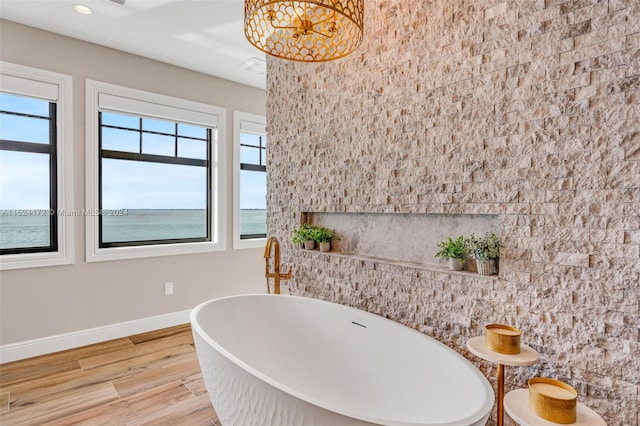 bathroom featuring a water view, hardwood / wood-style floors, and a tub