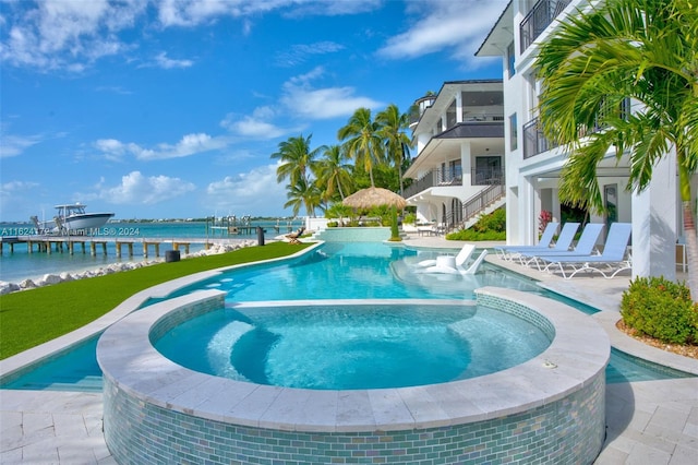 view of swimming pool featuring a water view and an in ground hot tub