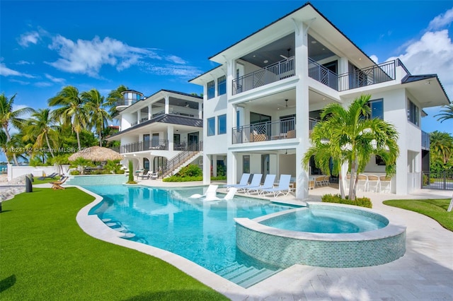 back of house with a patio area, a balcony, a yard, a pool with hot tub, and ceiling fan