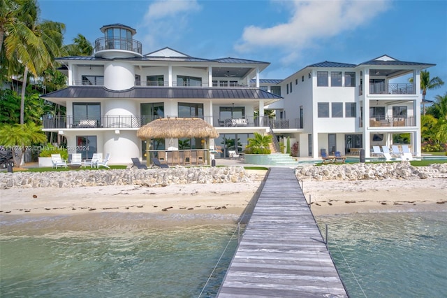 rear view of property featuring a view of the beach, a balcony, and a water view