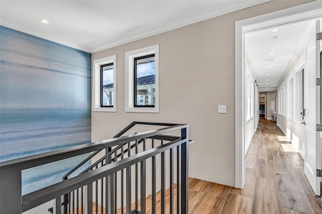 hall with ornamental molding and light hardwood / wood-style floors