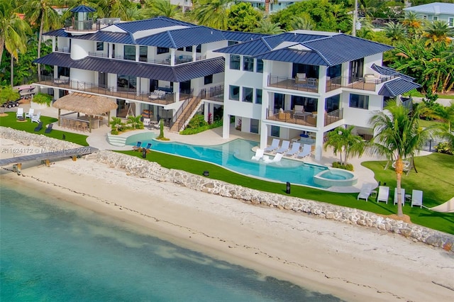 exterior space featuring a balcony, a water view, a beach view, and a patio area