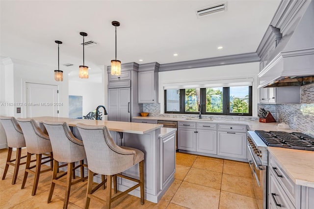 kitchen with pendant lighting, premium range hood, high end range, gray cabinetry, and a kitchen island