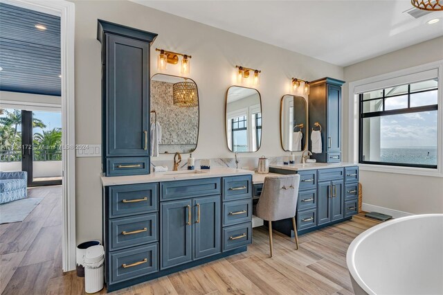 bathroom with hardwood / wood-style floors, vanity, a healthy amount of sunlight, and a bath