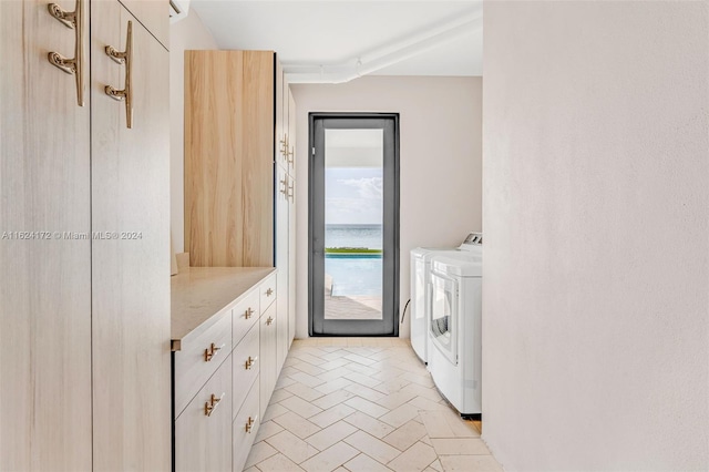 laundry area featuring a water view, cabinets, and washer and clothes dryer