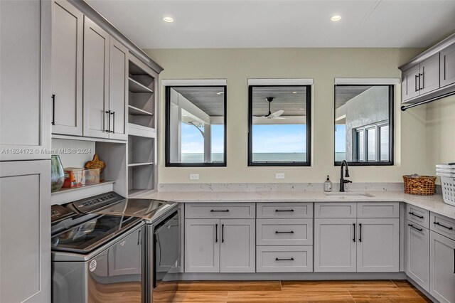 kitchen featuring light stone counters, sink, gray cabinets, and washer and dryer