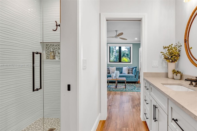 bathroom featuring vanity, wood-type flooring, a shower with door, and ceiling fan