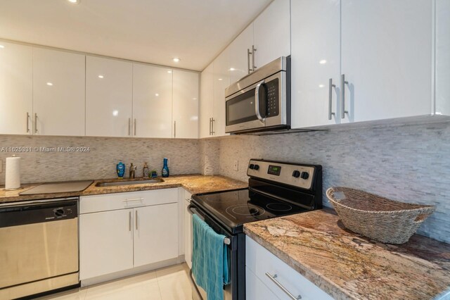 kitchen featuring sink, appliances with stainless steel finishes, backsplash, white cabinets, and light tile patterned flooring