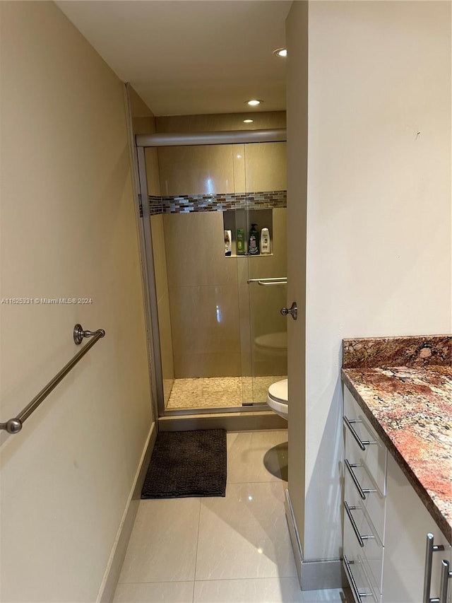 bathroom featuring vanity, toilet, an enclosed shower, and tile patterned flooring