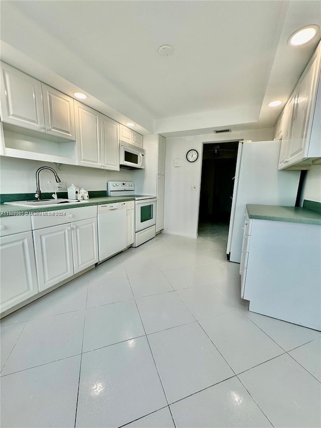 kitchen featuring white appliances, sink, light tile patterned floors, and white cabinets