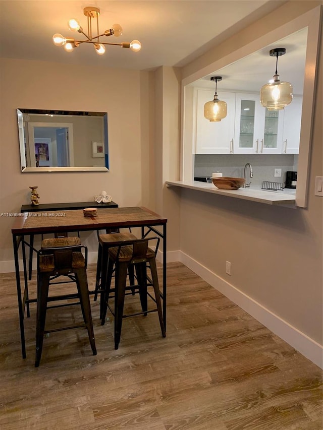 dining area with hardwood / wood-style flooring, a notable chandelier, and sink