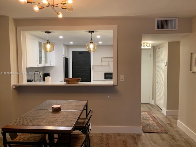 kitchen featuring kitchen peninsula, black microwave, white cabinets, and light hardwood / wood-style floors