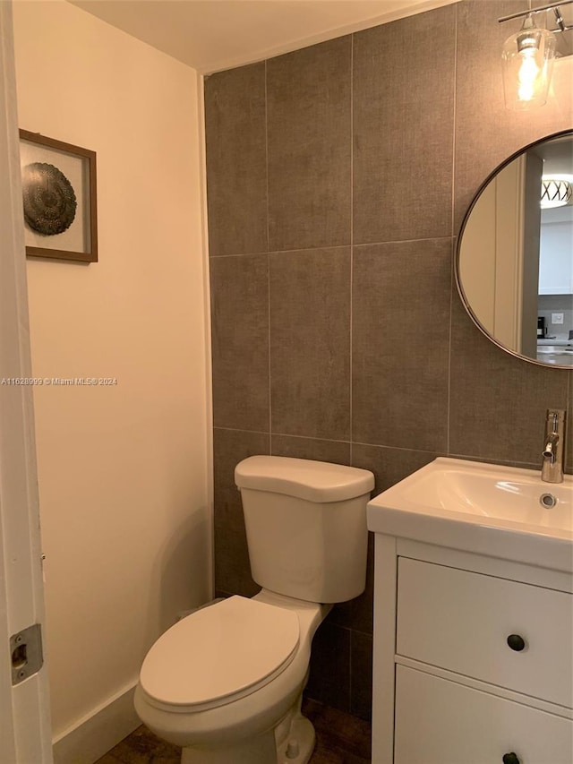 bathroom with vanity, toilet, and tile walls