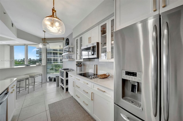 kitchen with stainless steel appliances, white cabinetry, light tile patterned floors, and hanging light fixtures