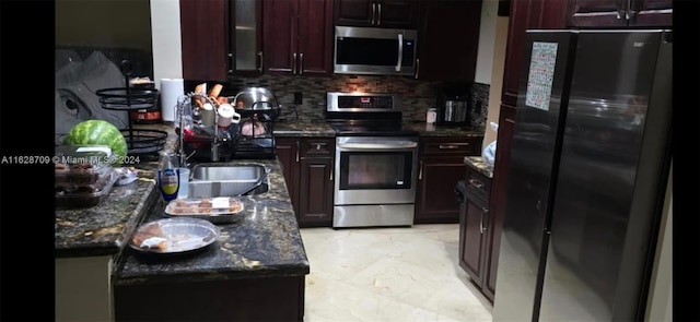 kitchen with stainless steel appliances, dark stone countertops, and tasteful backsplash