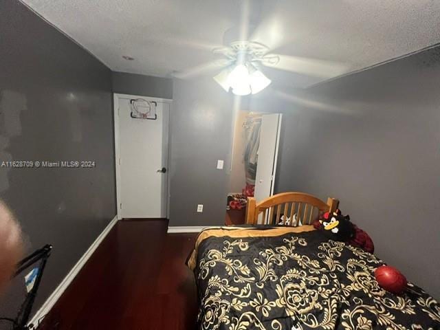 bedroom featuring ceiling fan, a textured ceiling, and dark hardwood / wood-style flooring