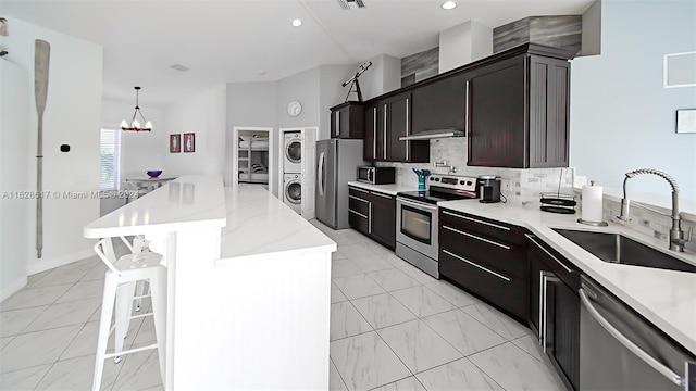 kitchen featuring appliances with stainless steel finishes, sink, stacked washer / drying machine, a center island, and light tile patterned flooring