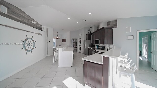 kitchen featuring dark brown cabinetry, a chandelier, light tile patterned floors, sink, and a breakfast bar area