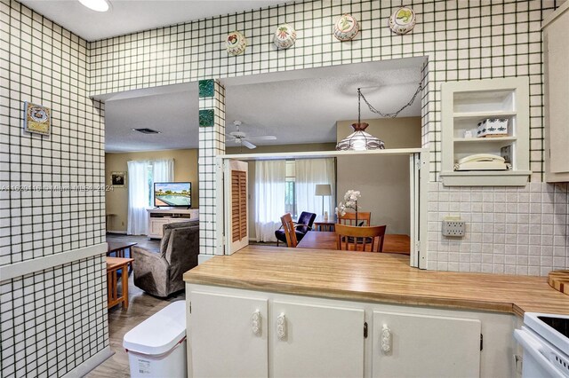 kitchen featuring pendant lighting, white range with electric stovetop, tasteful backsplash, ceiling fan, and light hardwood / wood-style floors