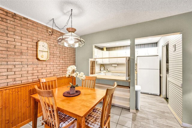 dining area with brick wall, wooden walls, and a textured ceiling