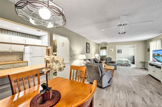 dining space featuring ceiling fan, a textured ceiling, and light wood-type flooring