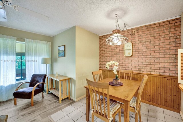 dining room featuring light hardwood / wood-style floors, brick wall, and a textured ceiling