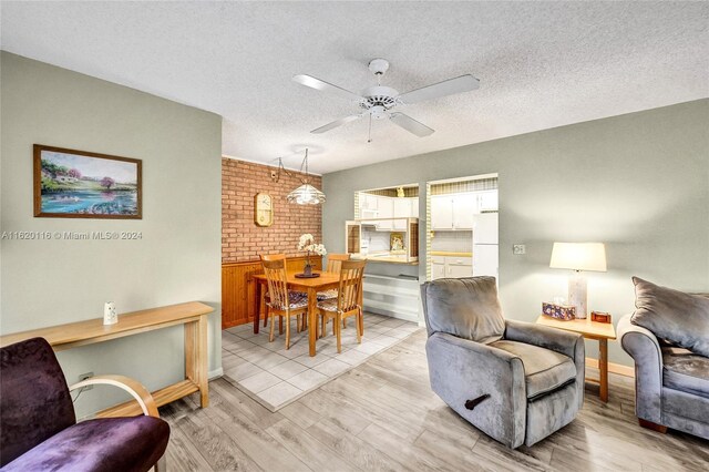 living room with ceiling fan, a textured ceiling, and light wood-type flooring