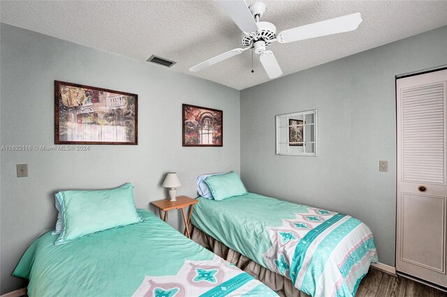 bedroom with dark hardwood / wood-style flooring, ceiling fan, and a textured ceiling