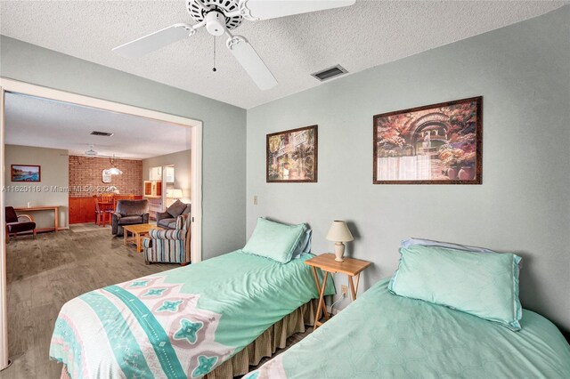 bedroom with ceiling fan, hardwood / wood-style floors, and a textured ceiling