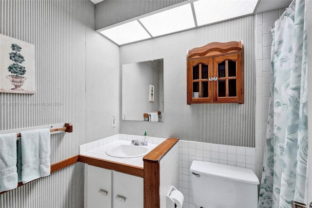 bathroom featuring vanity, a skylight, toilet, and a shower with shower curtain