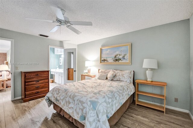 bedroom with wood-type flooring, connected bathroom, ceiling fan, and a textured ceiling