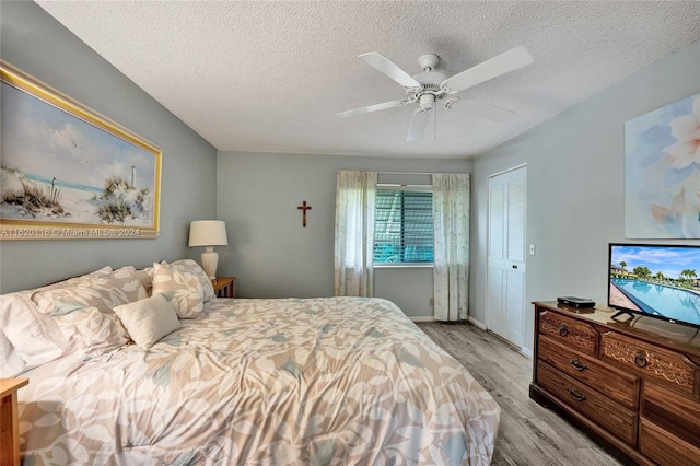 bedroom with light hardwood / wood-style flooring, a closet, a textured ceiling, and ceiling fan