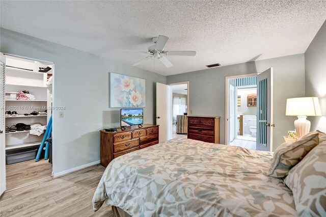 bedroom featuring ceiling fan, light hardwood / wood-style floors, a textured ceiling, a spacious closet, and a closet