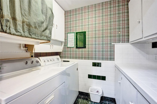 laundry area with washing machine and clothes dryer, cabinets, dark tile patterned flooring, and tile walls